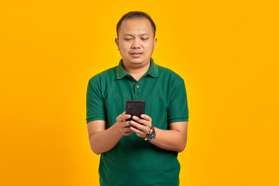 custom apps for small business - a man in a green shirt looking at a cell phone