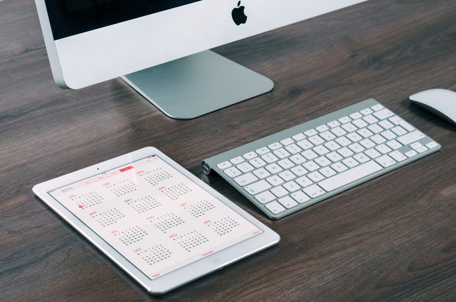 AI startup news - A sleek and modern office desk setup featuring an iMac, iPad with calendar, keyboard, and mouse.
