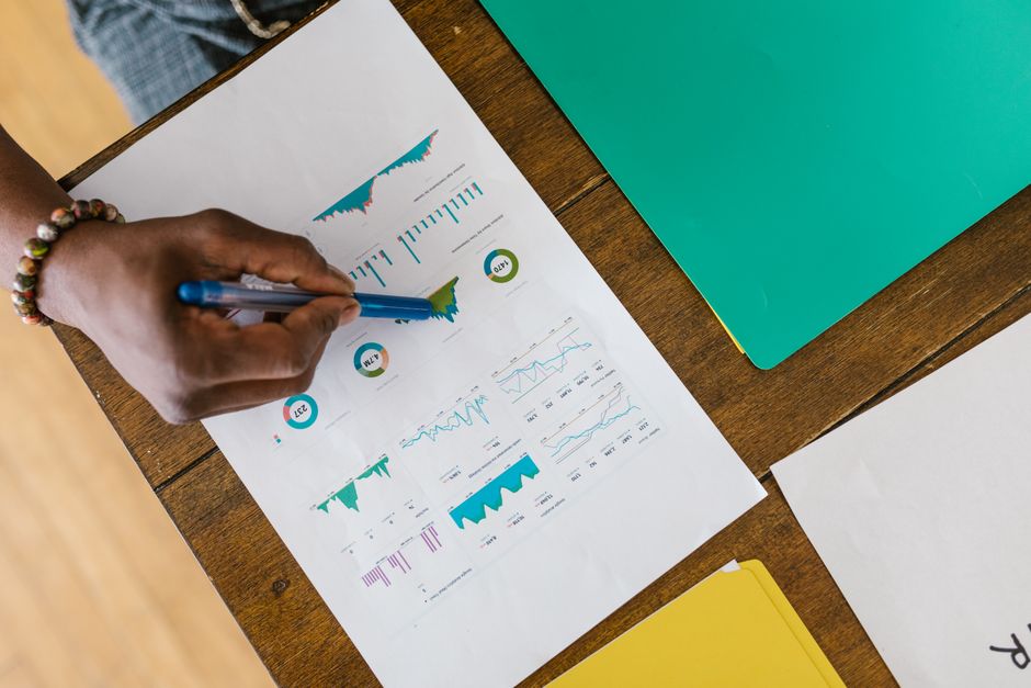AI startup news - Overhead view of a person analyzing business charts and graphs on paper.