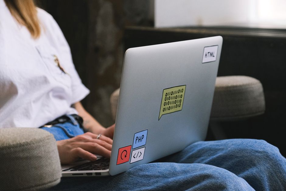 AI startup news - Person typing on a laptop with coding stickers, symbolizing remote work and freelancing.